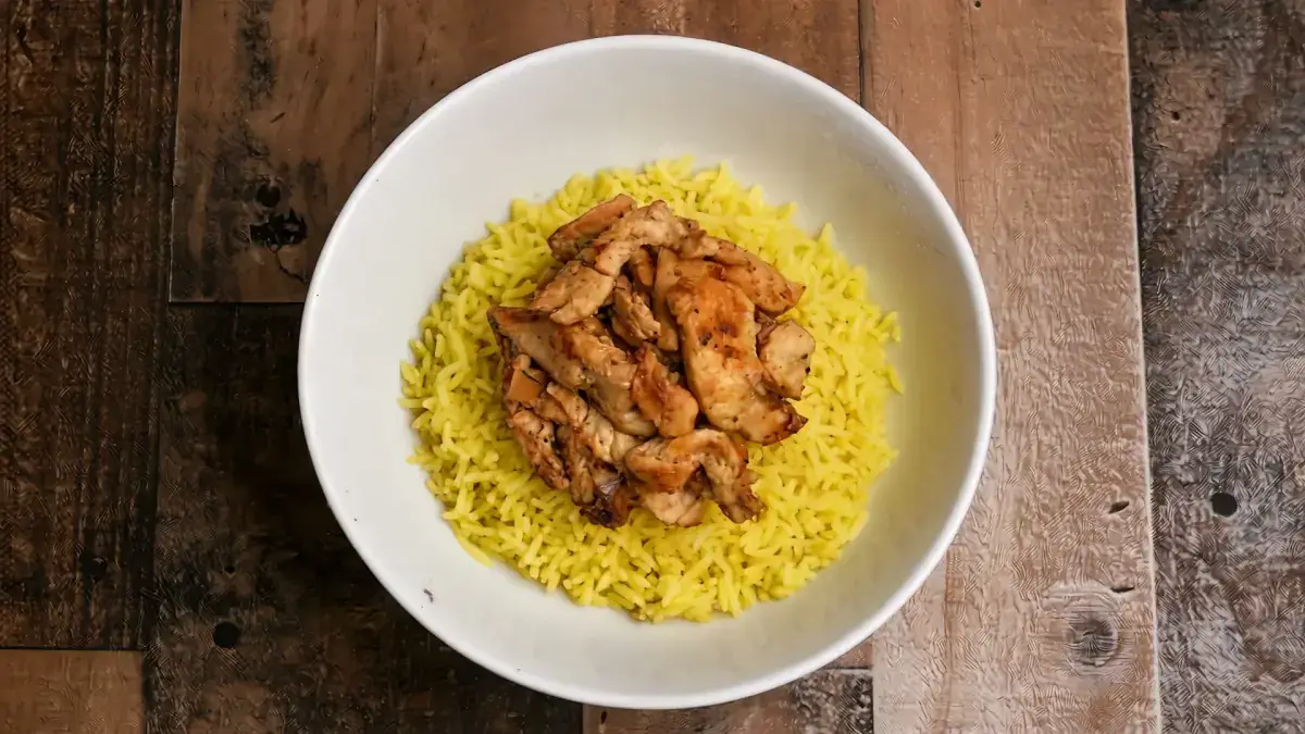 Chicken shawarma piled on saffron rice in a white bowl
