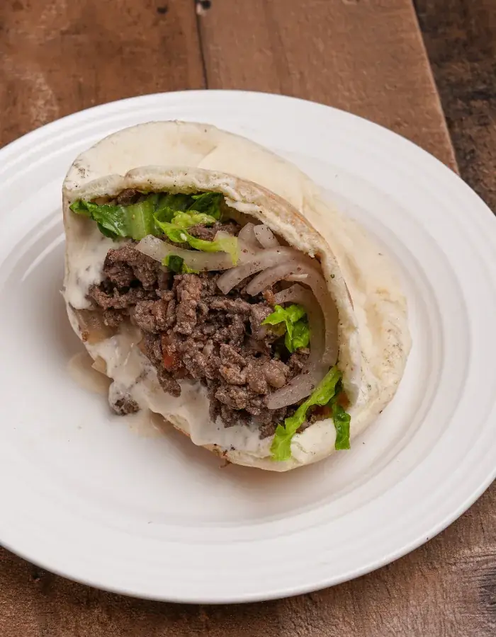 A pita pocket stuffed with gyro, lettuce, onions and garlic sauce
